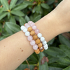 Three beaded bracelets on a wrist with a green leafy background